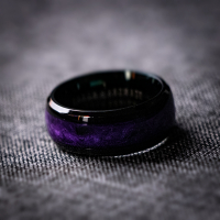 A black ring with iridescent violet pigments and pieces of black onyx stone inlaid around the band, creating a textured and organic pattern.